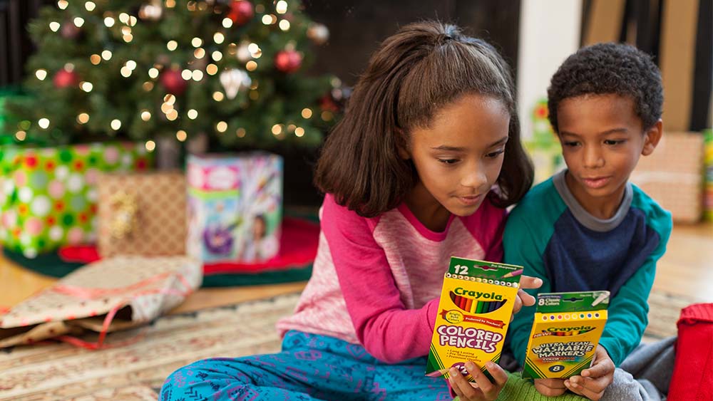 Children opening gifts in front of a Christmas tree.