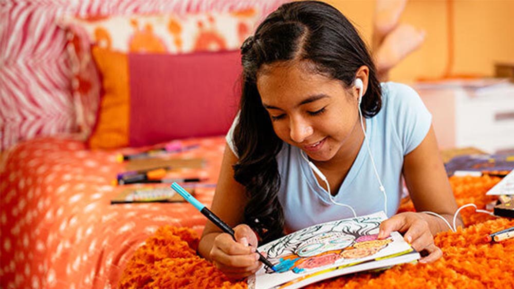 Teen girl on her bed with earbuds.